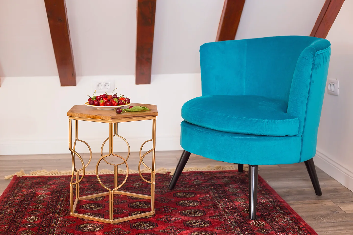 Teal velvet armchair and gold side table with fresh cherries in the Kaleta Loft inside Diocletian's Palace, Split